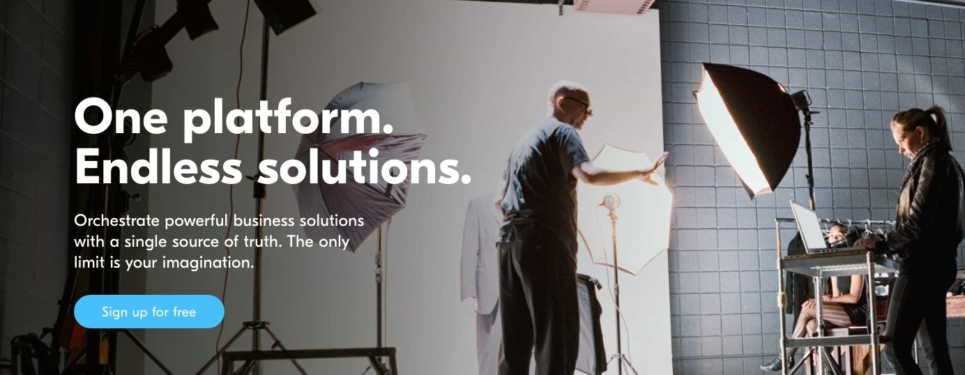 This image contains people  adjusting lighting on what appears to be the set for a photoshoot, with white text overlaying that reads "One platform. Endless solutions". It's a screenshot from the Airtable homepage